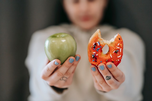 Girl holding apple and donut